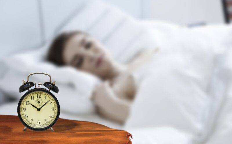 Child sleeping peacefully beside an alarm clock, dreaming of nighttime adventures